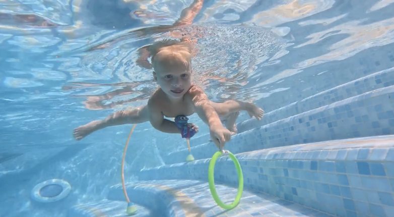 Kind zwemt ontspannen onder water naar een ring