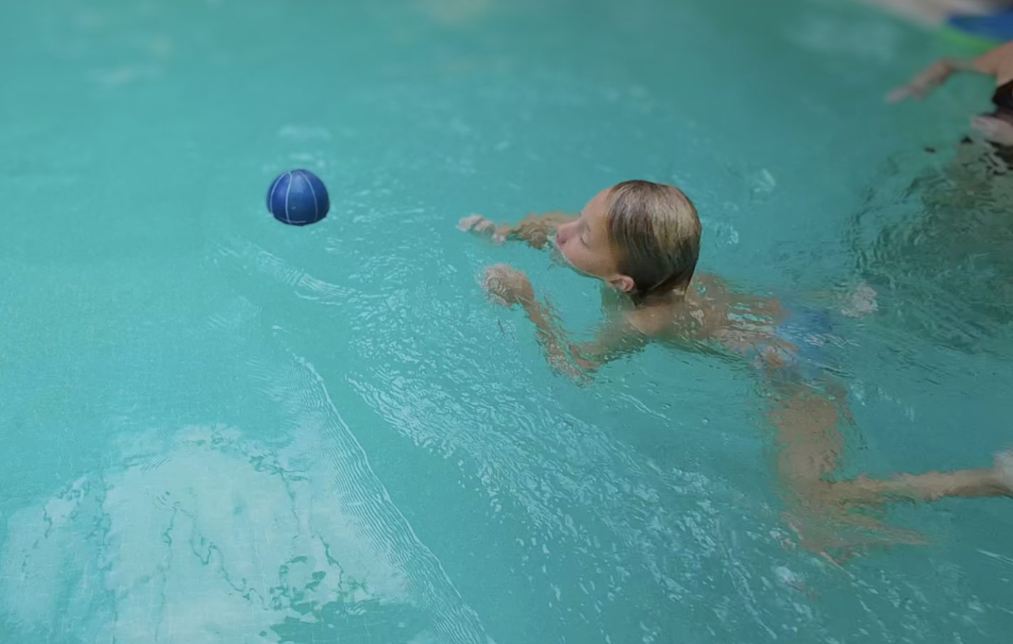 Kind zwemt naar een bal